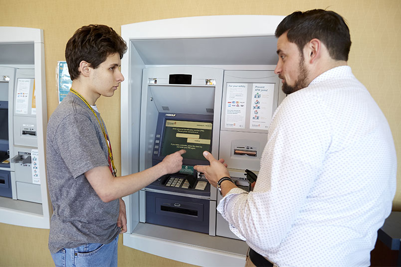 Walter Mayeer shows sophomore Ben DiVittorio how to use an ATM.