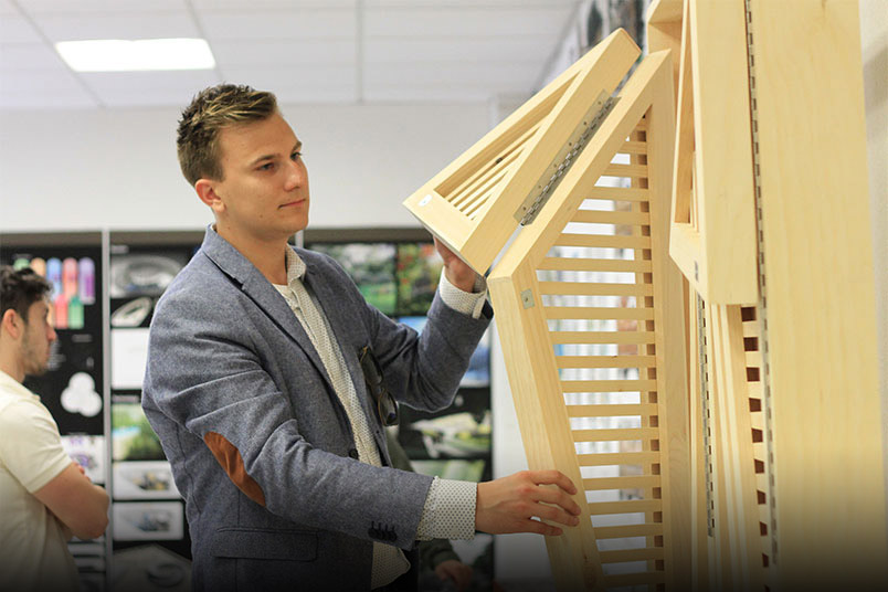 NYIT student Arkadiusz Chrobac demonstrates how the façade of his team’s building proposal would feature panels inspired by a leaf that would open and close to adjust how much light is let into the building.