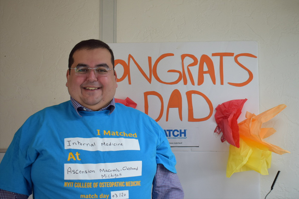 George Yassa shares his match in front of a sign made by his children.
