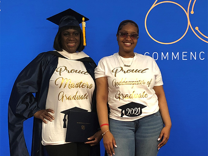 A student celebrates completing her master's degree with her goddaughter at the Stroll Across the Stage event on the New York City campus.