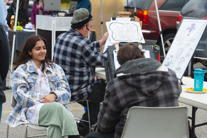 A student sits to have her caricature drawn on the Long Island campus.