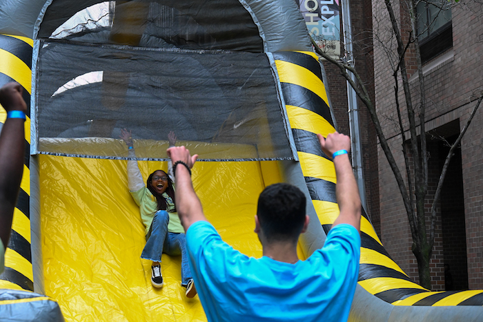 At the New York City Street Fair, student Pashence Glover completes the inflatable obstacle course by sliding to the end while classmate Ali Gedawi cheers her on..