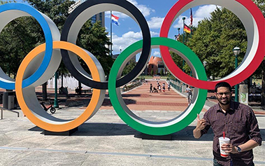 Alumni standing in front of Olympic rings