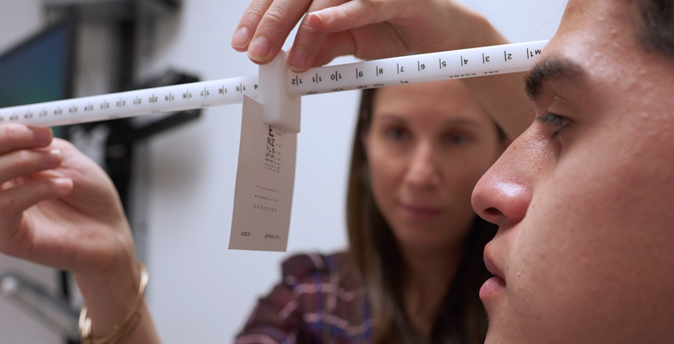 Patient is receiving an eye exam to determine if his vision has been affected by a potential concussion.