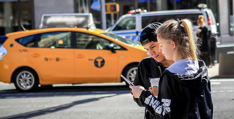 Two students on NYC street and cab driving by
