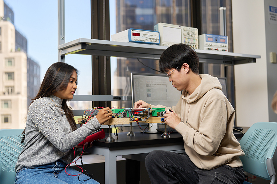 Two students work on an engineering project at the New York City campus.