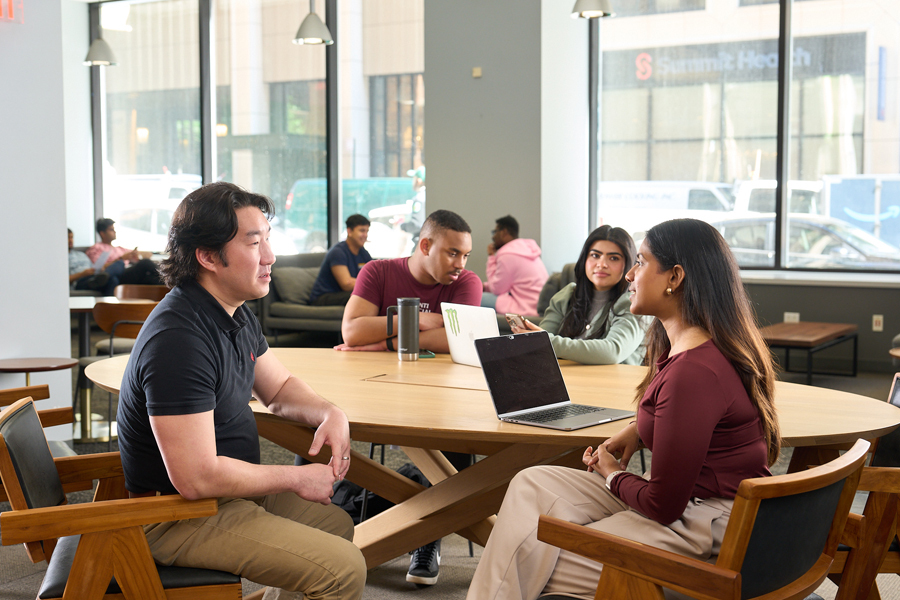 Four students convene at a wooden table at the New York City campus.