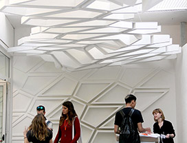 People standing in a white room decorated with wavy designs on the walls and above with wavy lighted panels.