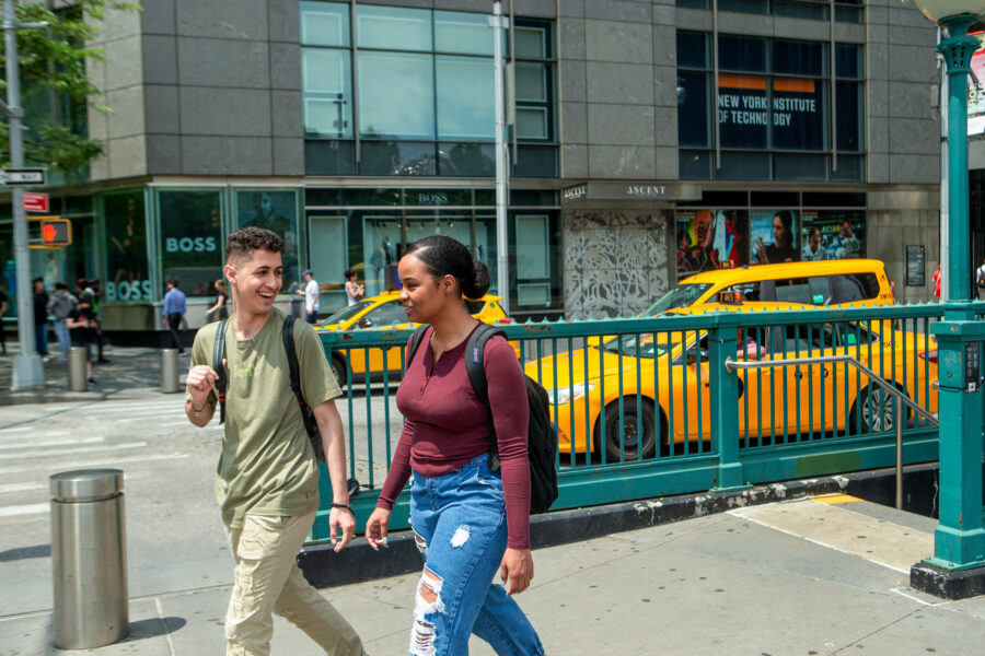 Two students walking by a New York City subway station