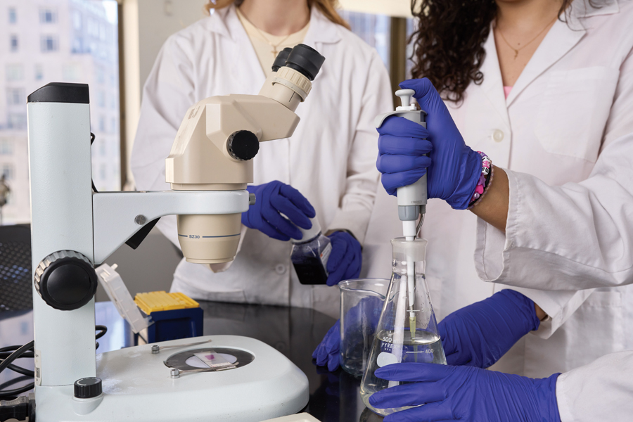 Researchers using a flask standing by a microscope