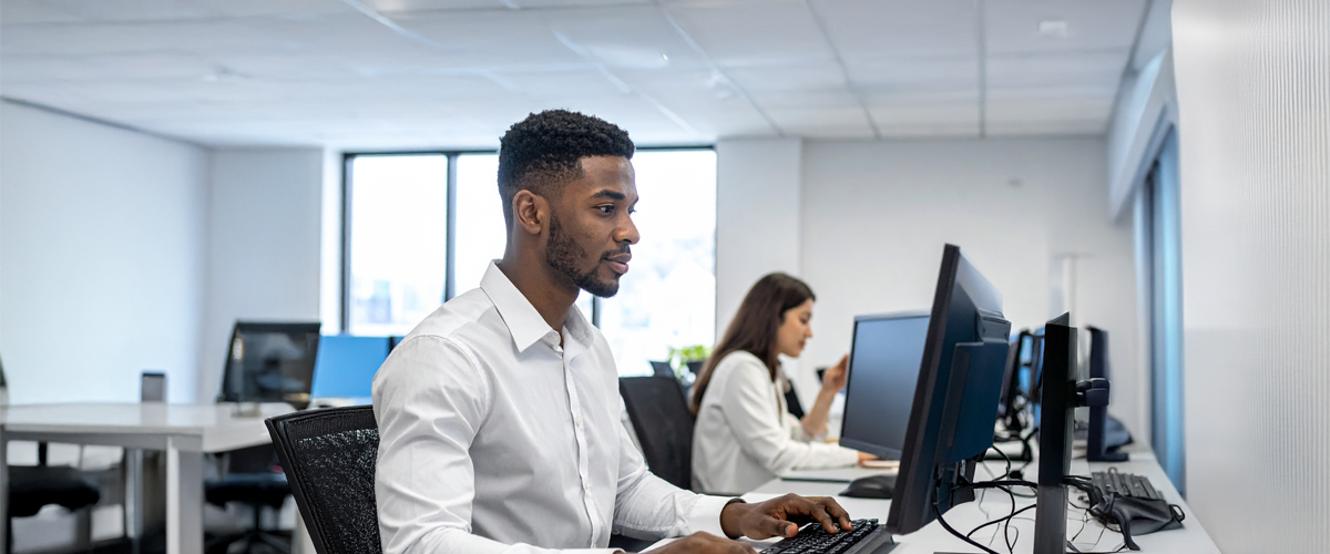 A man and woman working at computers in an office