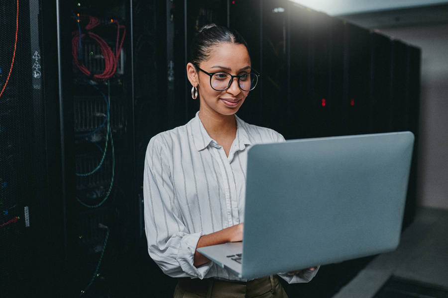 Woman holding a laptop in-front of server racks