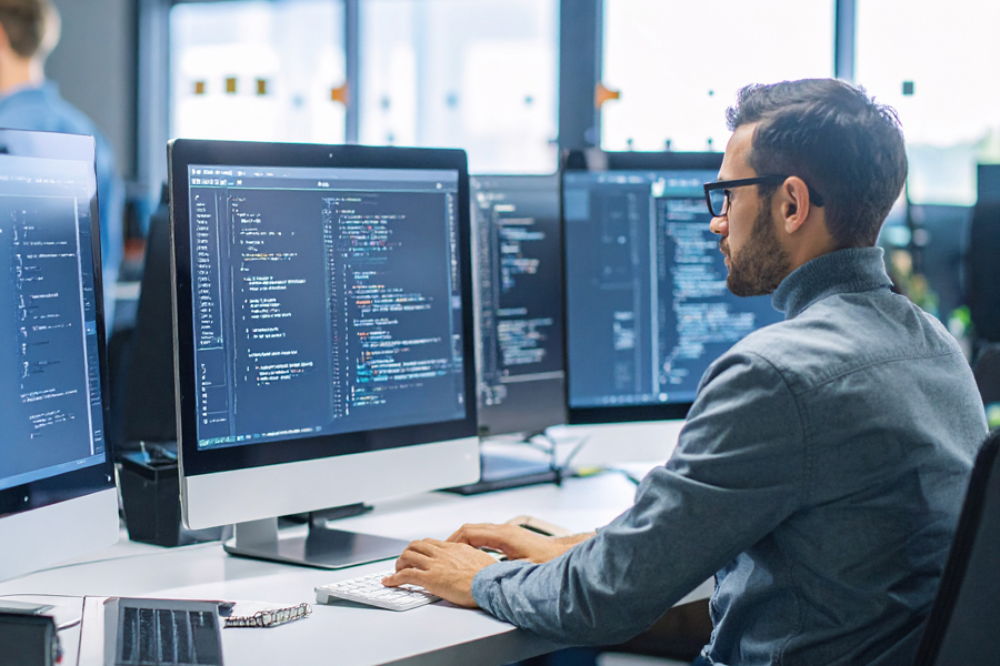 A man in an office with glasses editing code