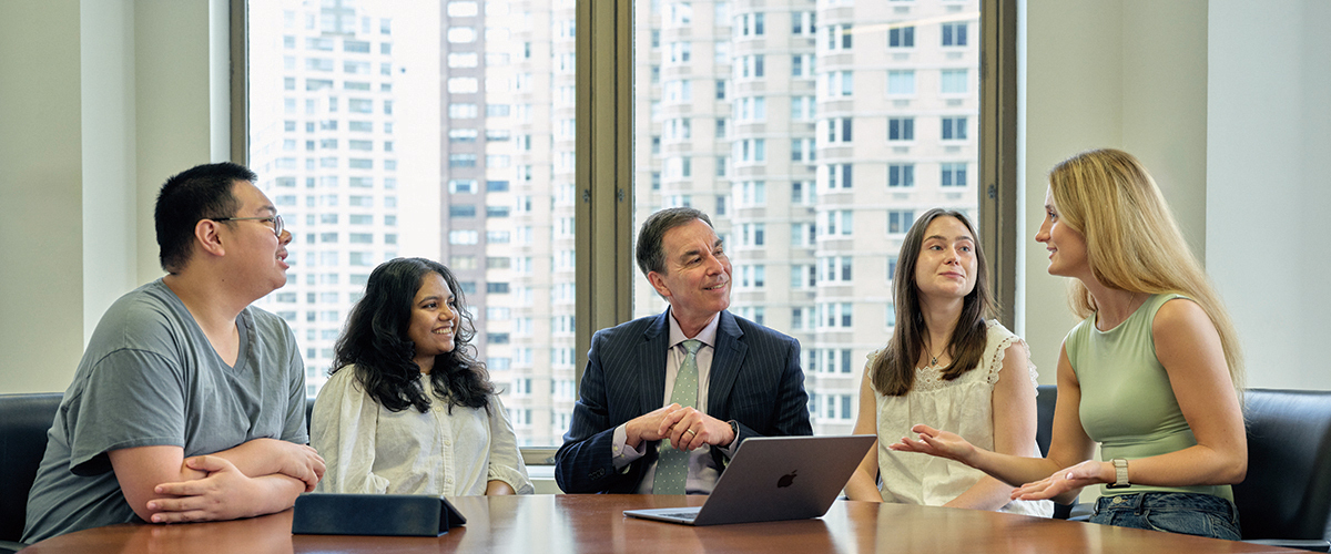 President Balentine meets with students at a large conference table at the New York City campus.