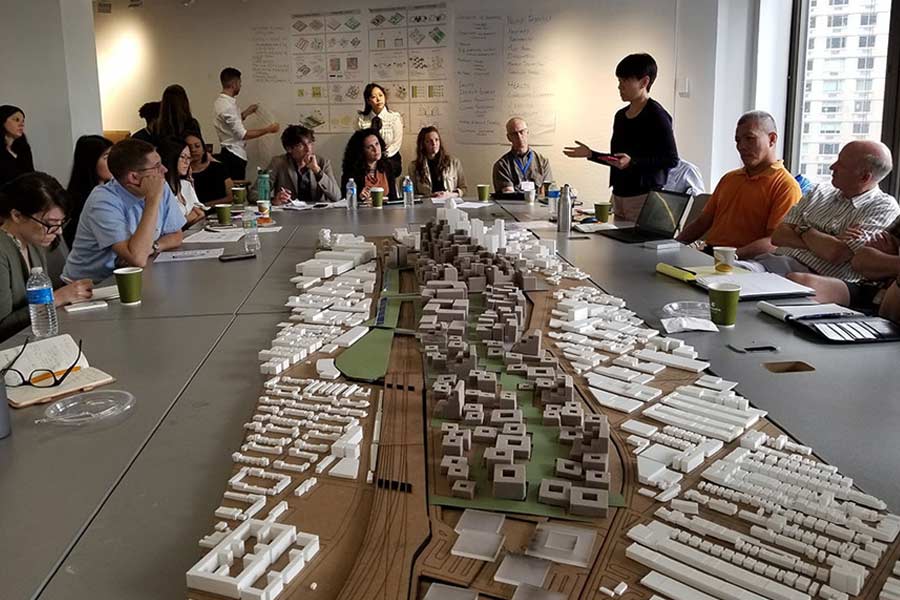 A lecture at a table with a city model on it