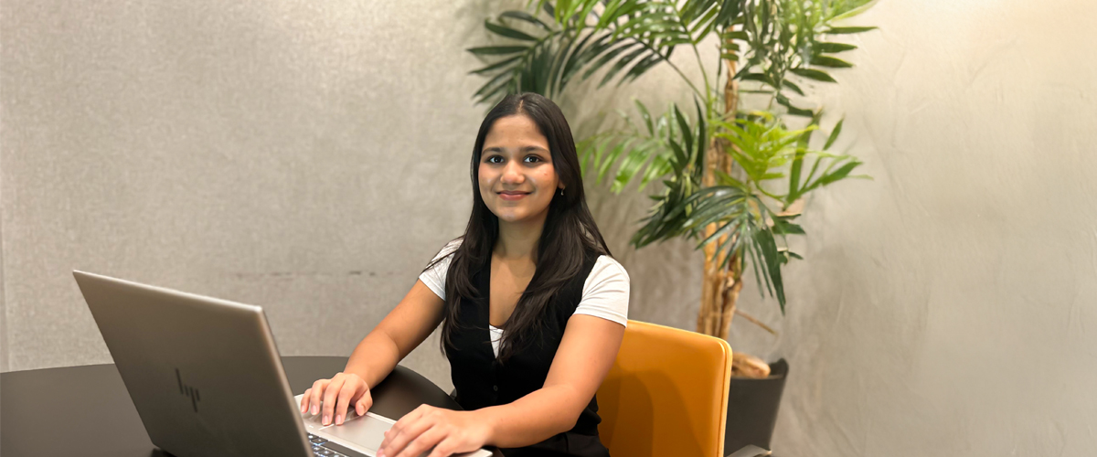 Ananya More sitting at a desk with a laptop