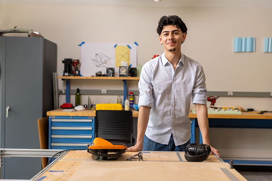 An architecture student stands with his hand on a drafting table in the studio.