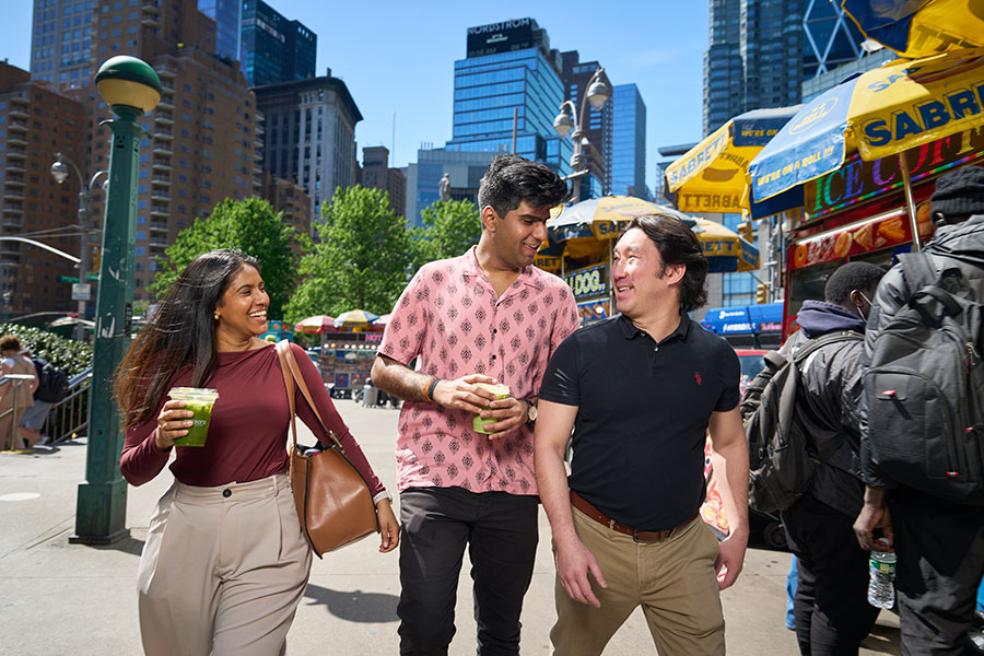 Three students walk in the city holding matcha drinks.