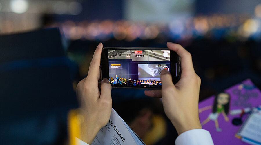 A person takes a video on a cell phone during a commencement ceremony.