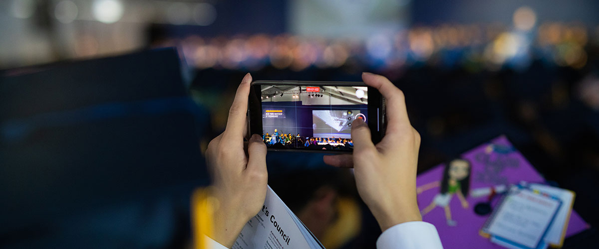 A person takes a video on a cell phone during a commencement ceremony.