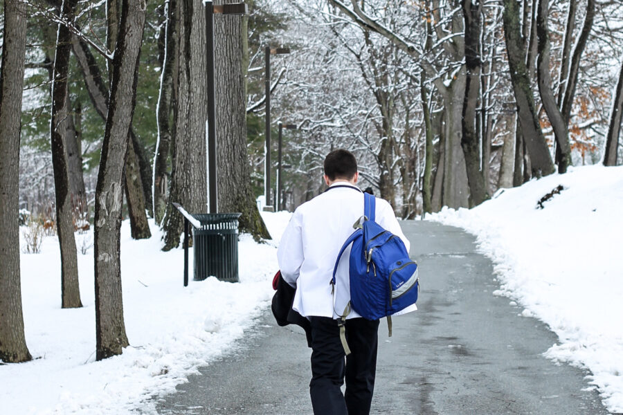 Student walking on a path lined with snow