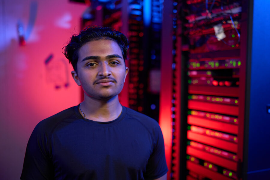 Tejas Attavar standing in front of computer servers.