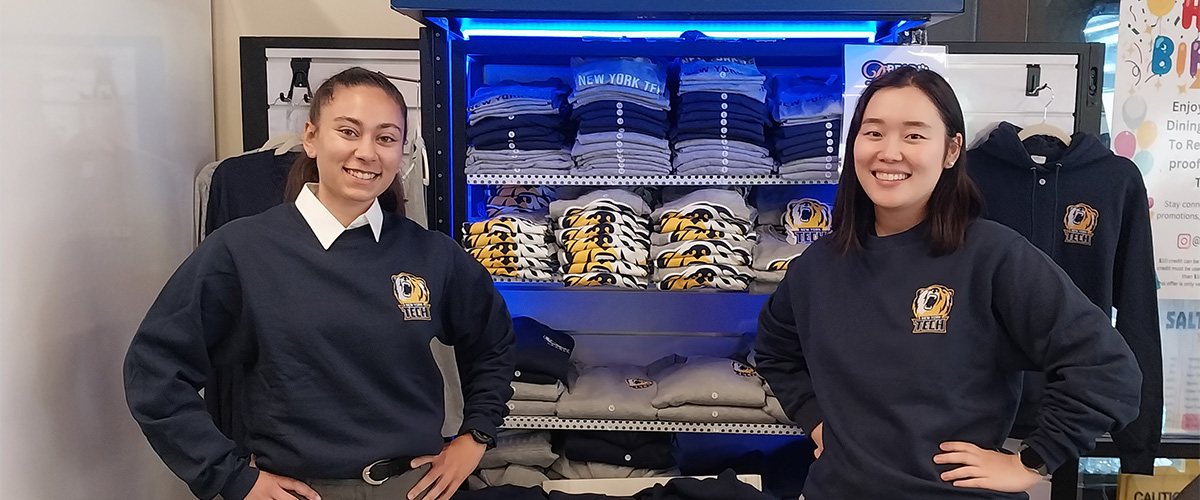 Two students standing in front of Bear Boutique Booth with shirts and merchandise.