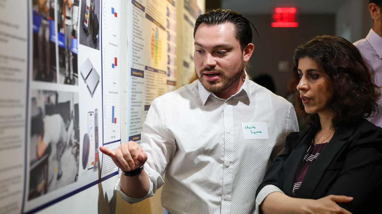 Charles Sigueza explaining his poster to an attendee
