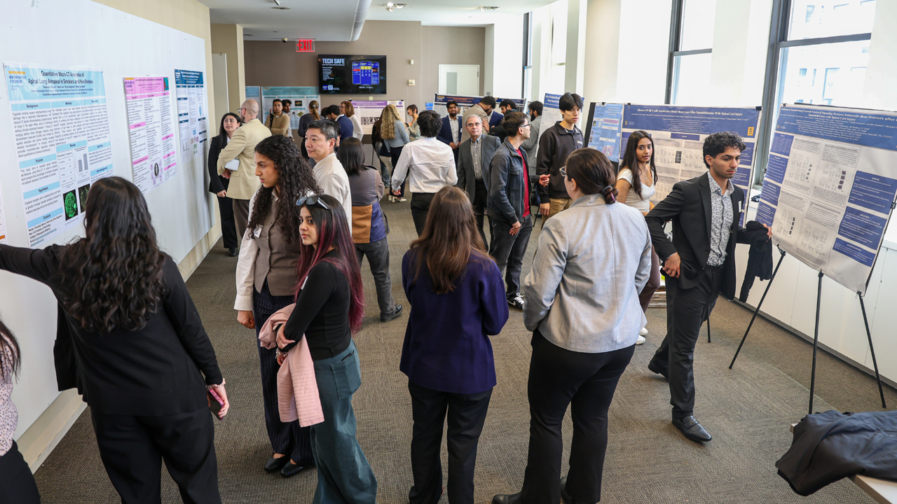 Attendees looking at posters and speaking to student presenters