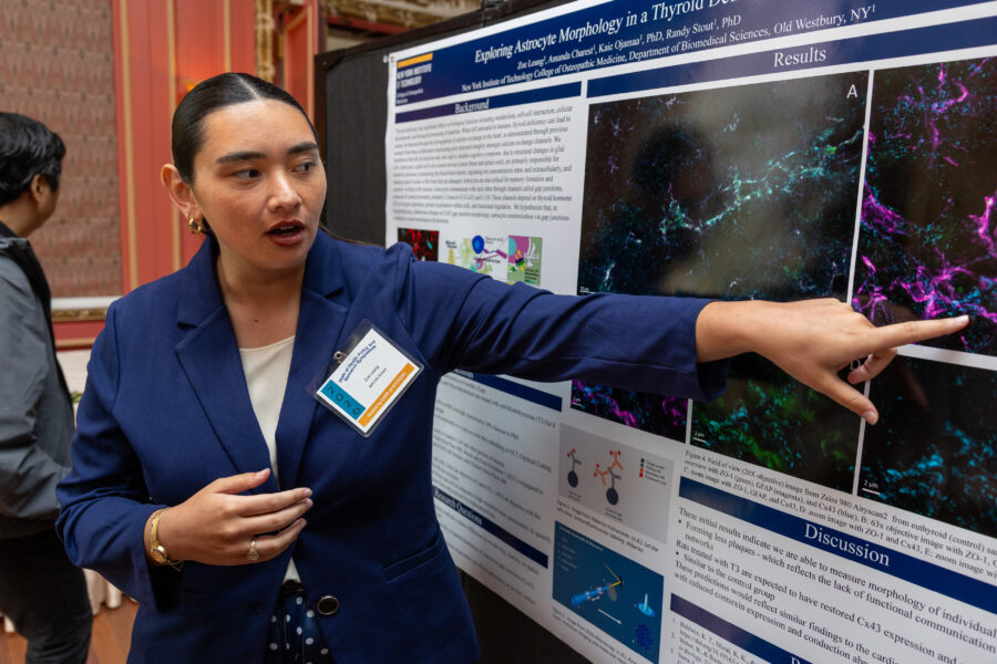 NYITCOM student standing next to her poster
