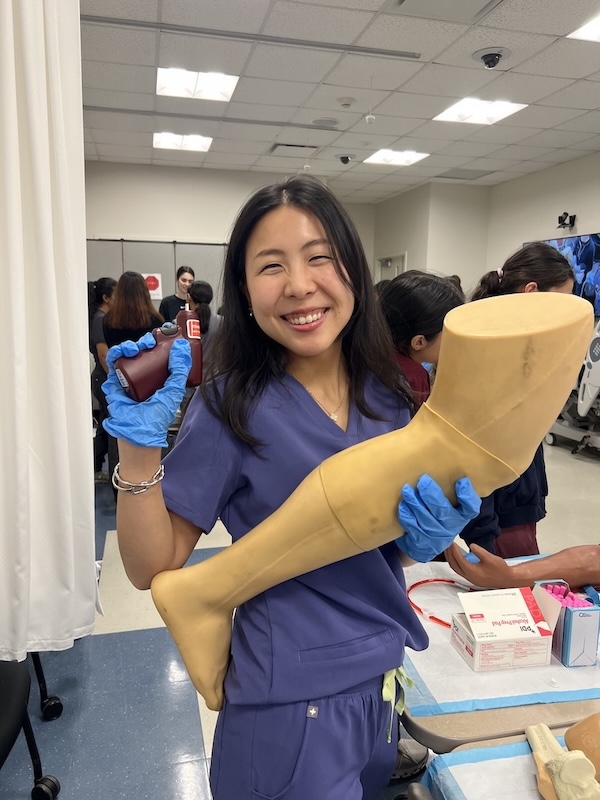 Connie Rim in scrubs holding a tool and mannequin leg