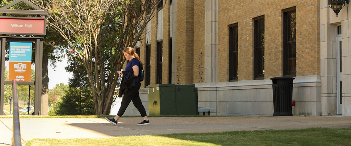 Student walking by a building