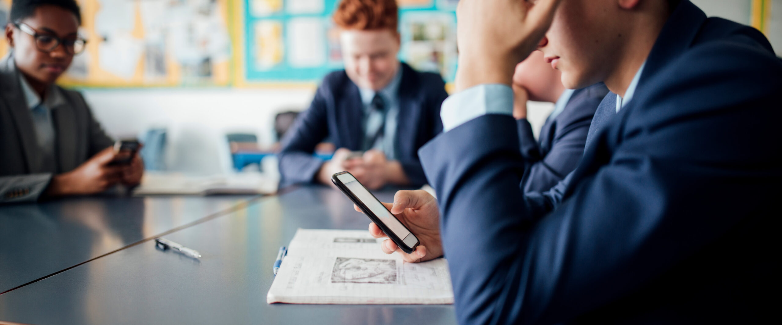 Student sitting in a classroom looking at a phone