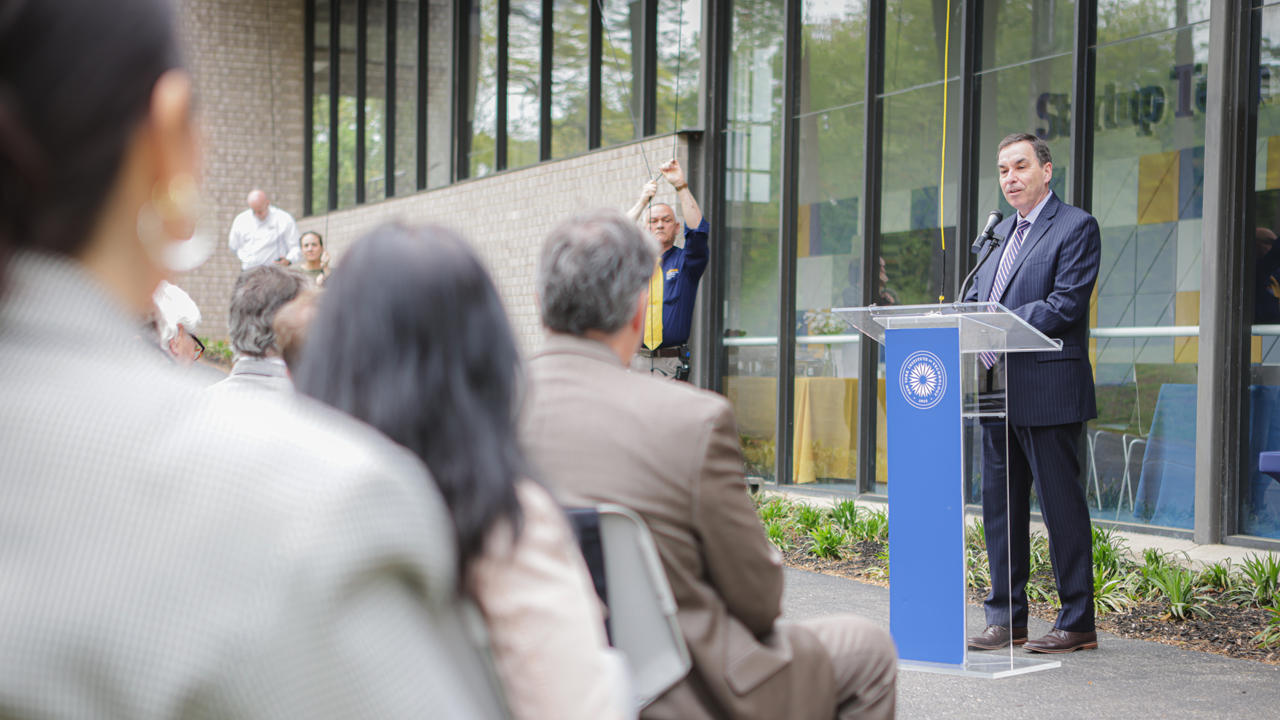 New York Tech President Jerry Balentine speaking at a podium