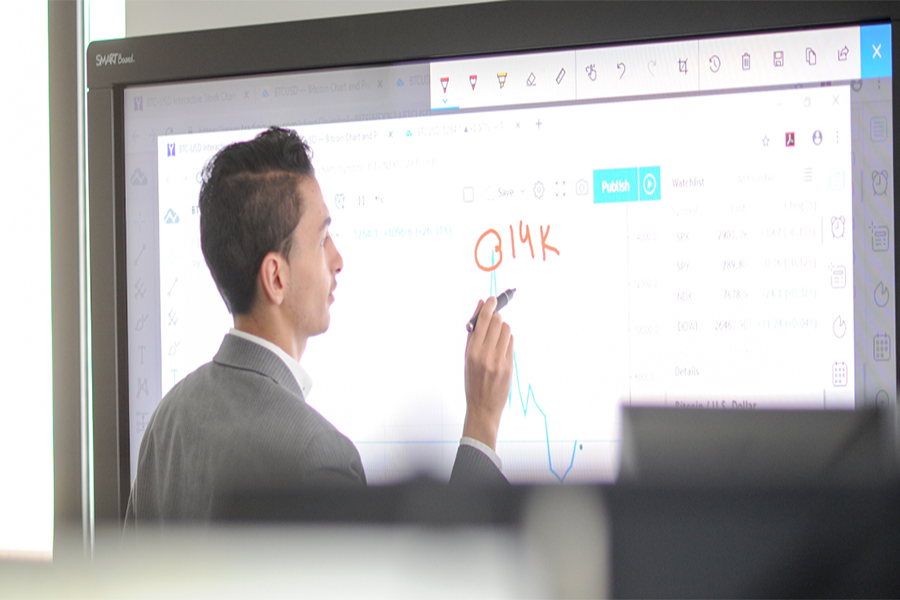 A student writes on a smart board with a marker.
