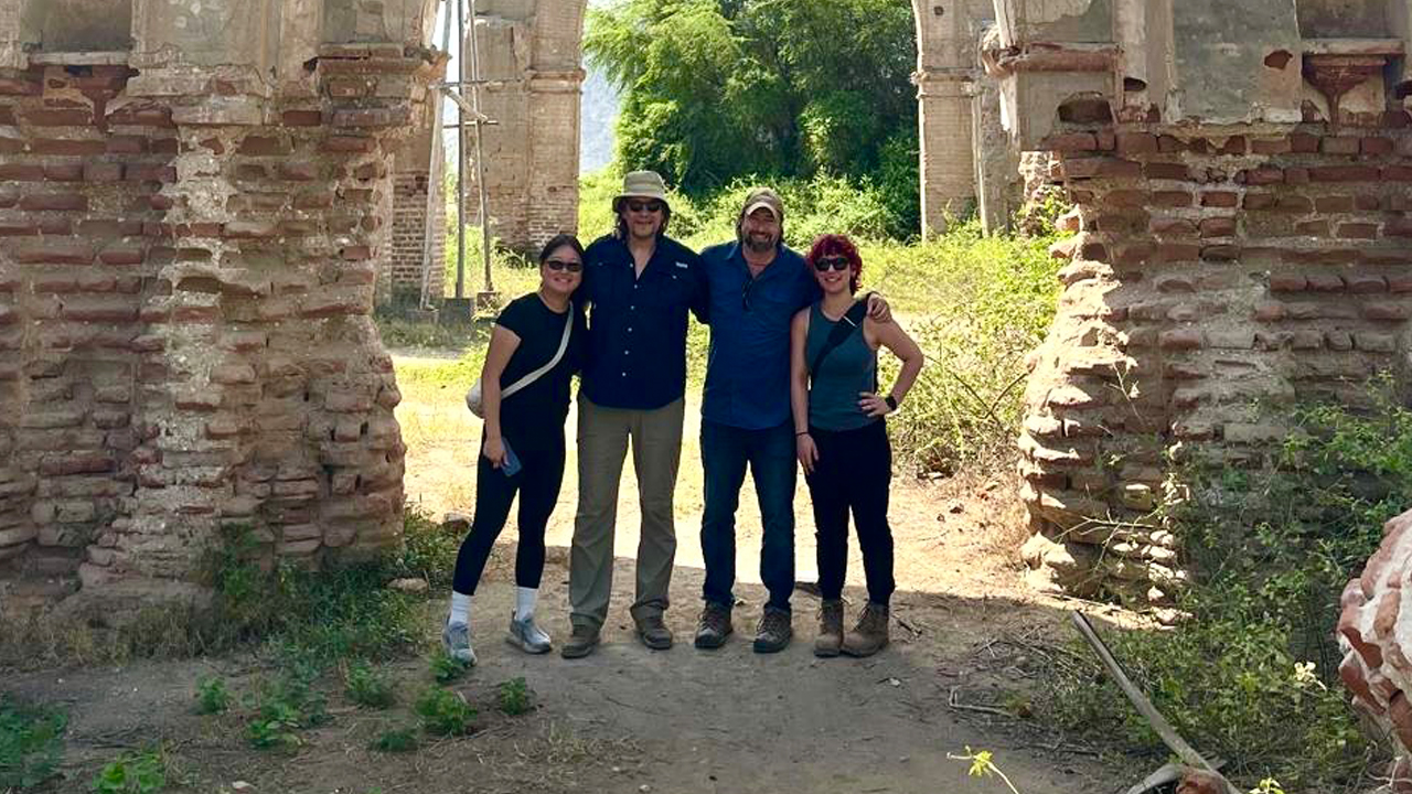 Group photo of students and professors under an ancient archway