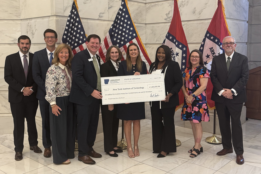 Group of people holding a large check standing in front of flags