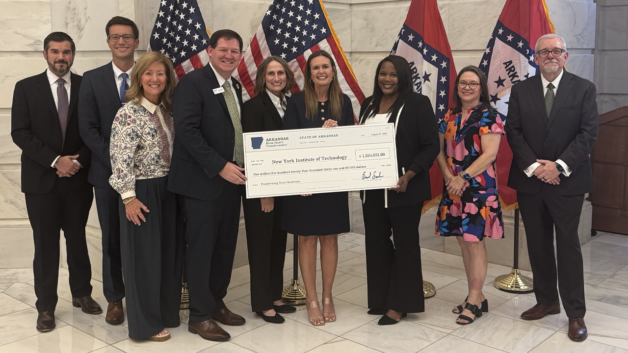 Group of people holding a large check standing in front of flags