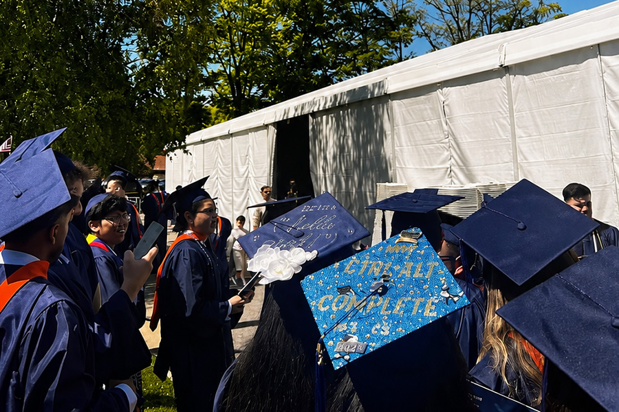 Students in cap and gown waiting to enter the commencement tent