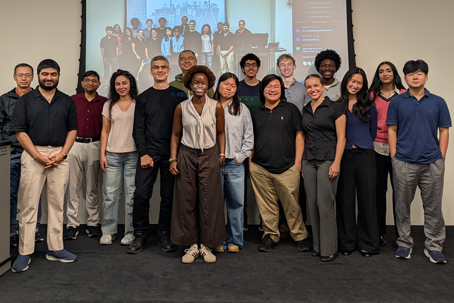 Group of students and faculty standing in front of a screen