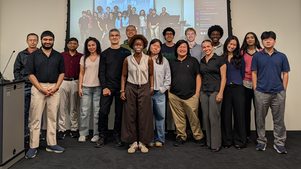 Group of students and faculty standing in front of a screen