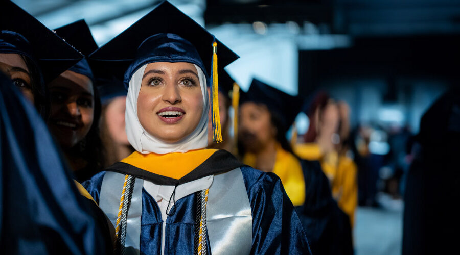 Female student smiling in a crowd of fellow graduates.