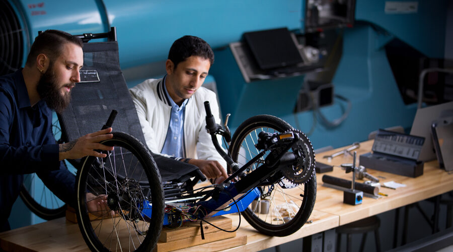 Two graduate students work on wheels for a device.