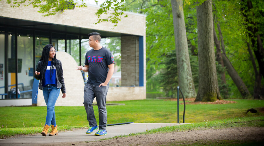 Two students are walking along a path at New York Tech's Long Island campus.