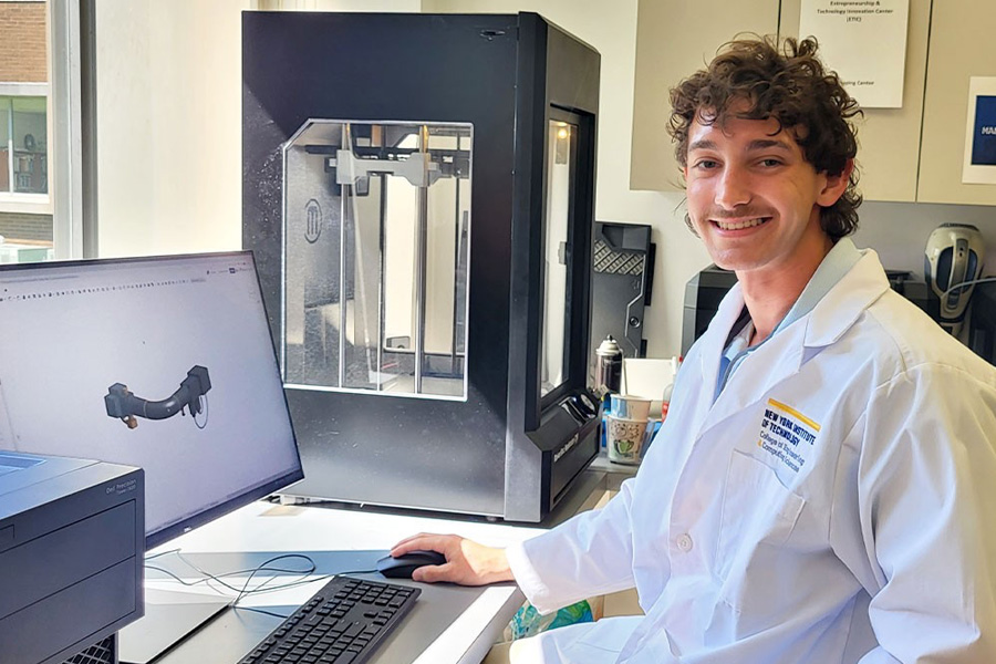 Brandon Castellano at a computer next to a 3-D printer